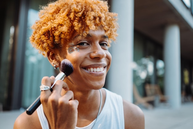 Visagista afroamericano che tiene il pennello e prepara il trucco