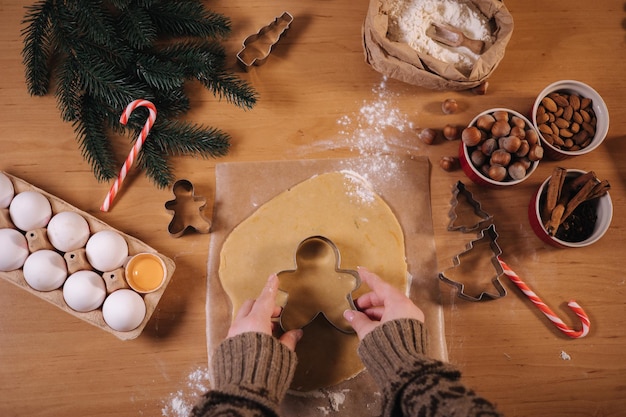 Visione in prima persona della donna che fa il pan di zenzero a casa femmina che taglia i biscotti di pasta di pan di zenzero