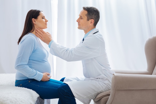 Visita programmata. Bella giovane donna mantenendo il sorriso sul viso e seduto di fronte al suo medico mentre fa il controllo sanitario