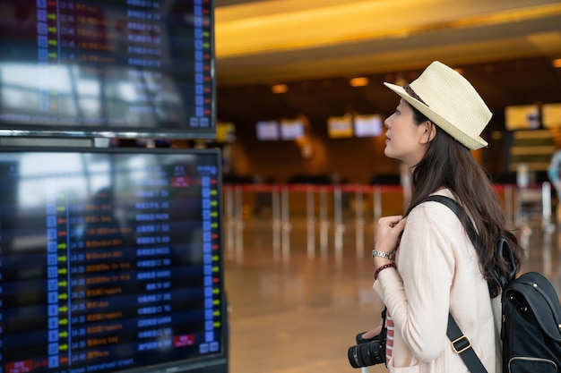 visitatore asiatico che cerca l'orario in aeroporto. alla ricerca del suo volo.