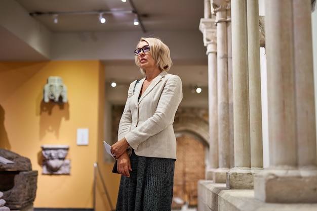 Visitatore donna matura vicino alle colonne nel museo storico historical