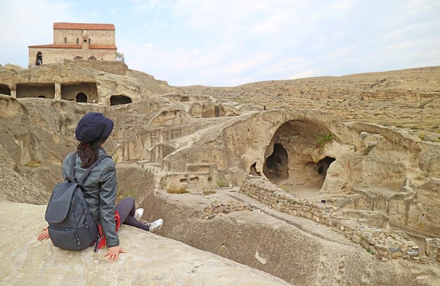 Visitatrice seduta sulla roccia delle rovine della città della grotta di Uplistsikhe, situata vicino alla città di Gori in Georgia