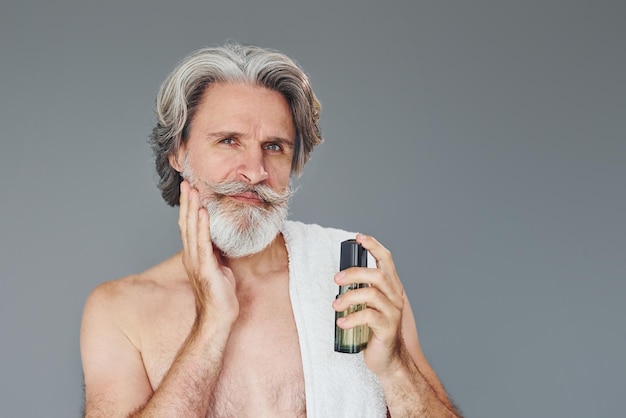 Viso fresco e pulito L'uomo anziano moderno ed elegante con i capelli grigi e la barba è al chiuso