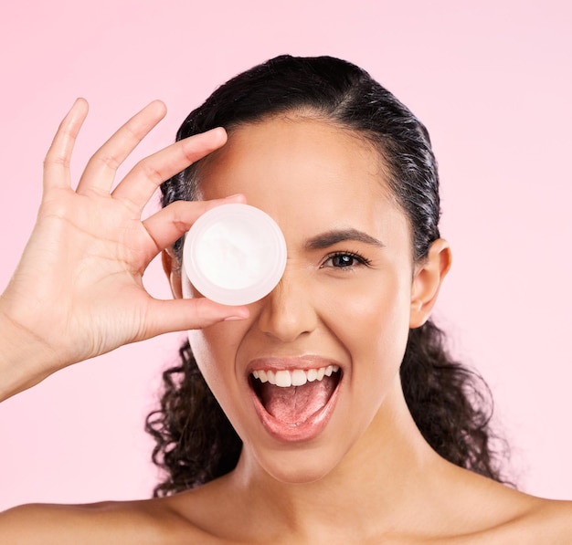 viso per la cura della pelle e donna eccitata con contenitore di crema in studio isolato su sfondo rosa ritratto modello naturale e felice con idratante protezione solare cosmetica o prodotto dermatologico per il benessere