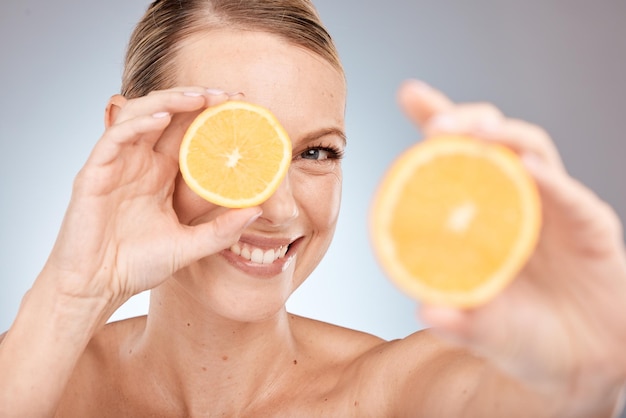 Viso ritratto cura della pelle e donna con limone in studio isolato su uno sfondo grigio Cibo benessere e felice modello femminile che tiene agrumi per una dieta sana vitamina c o nutrizione e bellezza