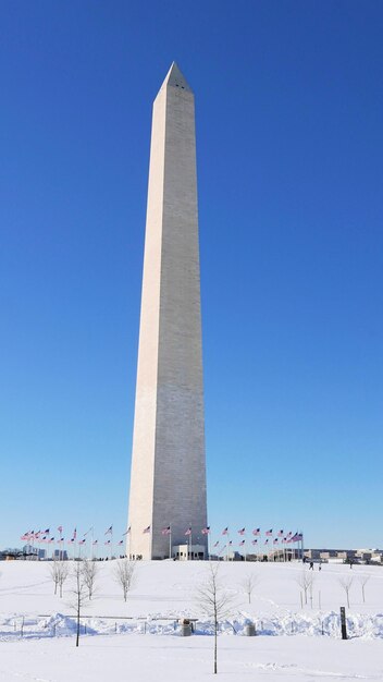 Vista a bassa angolazione del monumento a Washington sotto la neve contro un cielo blu limpido