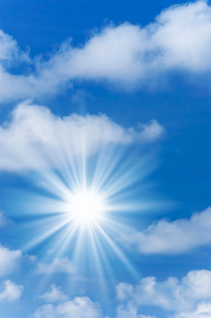 Foto vista a bassa angolazione del sole luminoso che splende in un cielo nuvoloso blu