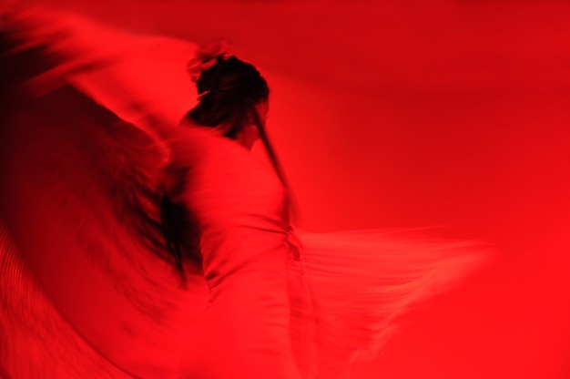 Vista a bassa angolazione di una donna che balla sullo sfondo rosso