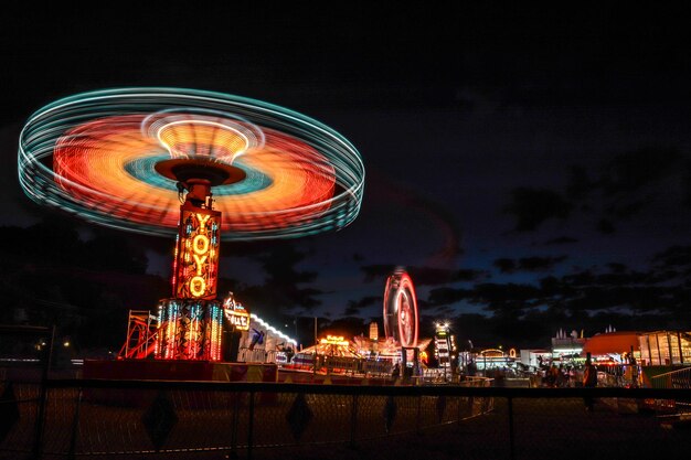 Vista a basso angolo della ruota panoramica illuminata nel parco divertimenti di notte