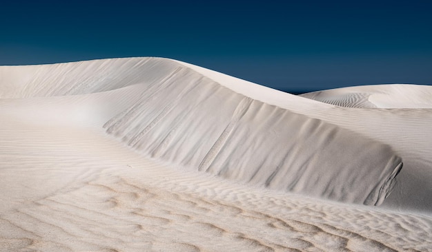 Vista a basso angolo delle dune di sabbia contro un cielo blu limpido