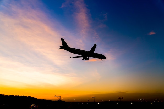 Vista a basso angolo di un aereo a silhouette che vola contro il cielo durante il tramonto