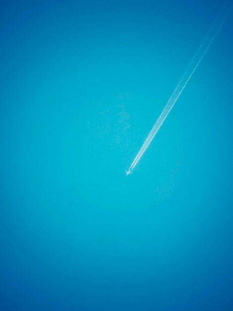 Vista a basso angolo di un aereo che vola contro un cielo blu limpido