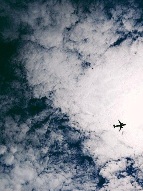 Vista a basso angolo di un aereo che vola in un cielo nuvoloso