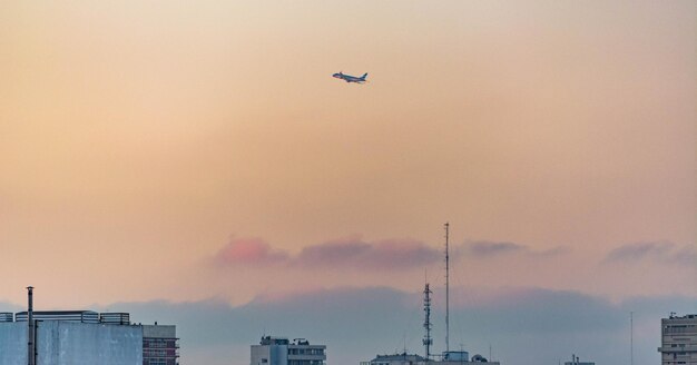 Vista a basso angolo di un aereo che vola sopra gli edifici durante il tramonto