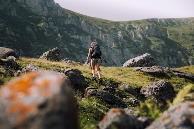 Vista a basso angolo di un escursionista femminile con uno zaino che cammina sulla montagna
