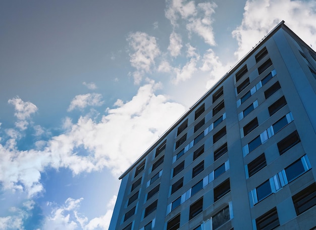 Vista a basso angolo di un grattacielo con finestre blu e cielo nuvoloso e luce solare generativa ai