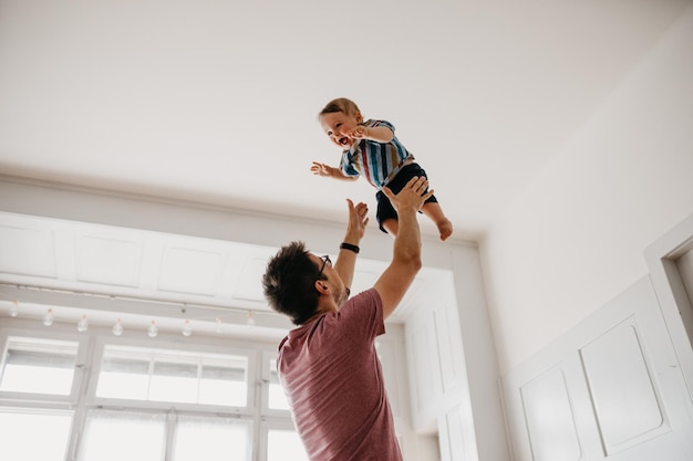 Vista a basso angolo di un padre giocoso che cattura il figlio a casa