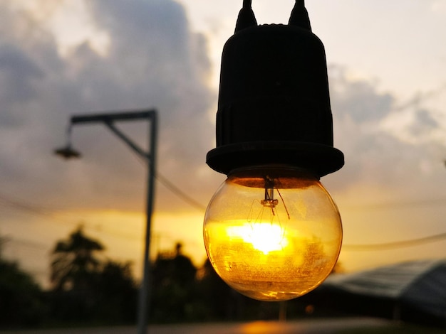 Vista a basso angolo di una lampadina illuminata contro il cielo al tramonto