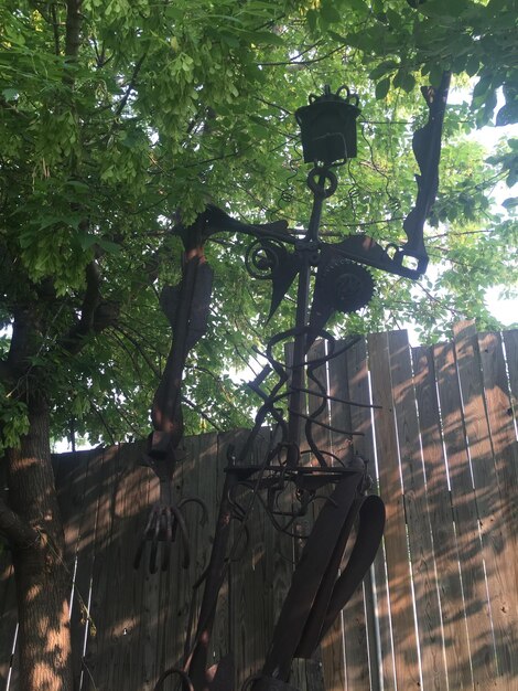 Vista a basso angolo di una scultura di rottami di metallo contro una recinzione di legno