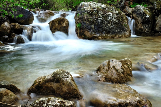 Vista a lunga esposizione di un fiume nascosto in Crimea Ucraina Una pietra incastonata su uno schema d'acqua sfocato è l'ideale per l'uso in background