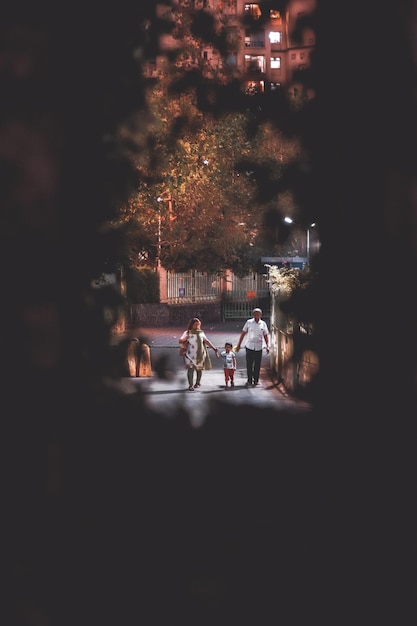 Vista a mezza distanza di una famiglia che si tiene per mano mentre cammina sulla strada
