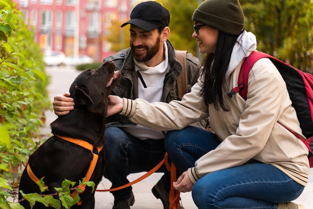 Vista a tutta lunghezza degli sposi felici che si rilassano nel paesaggio autunnale con il loro cane marrone Uomo e donna che accarezzano il loro Labrador