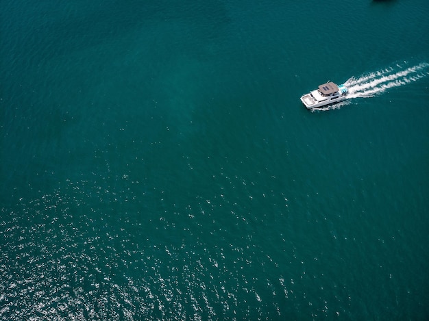 Vista a volo d'uccello della barca a motore bianca che si muove velocemente, la nave lascia una bella traccia bianca dietro; concetto di canottaggio.