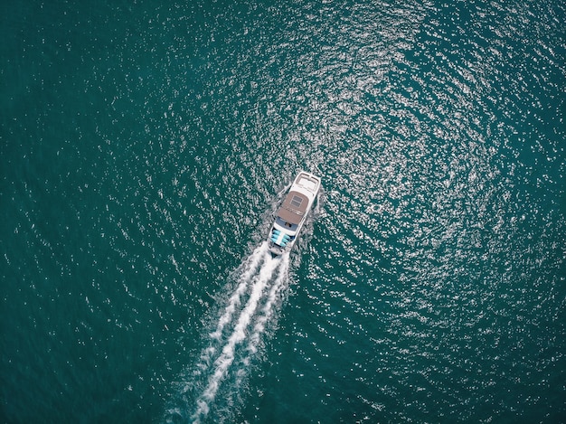 Vista a volo d'uccello della barca a motore bianca che si muove velocemente, la nave lascia una bella traccia bianca dietro; concetto di nautica.