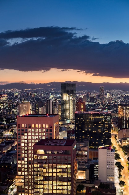 Vista ad alta angolazione degli edifici illuminati dalla città del Messico durante un tramonto estivo
