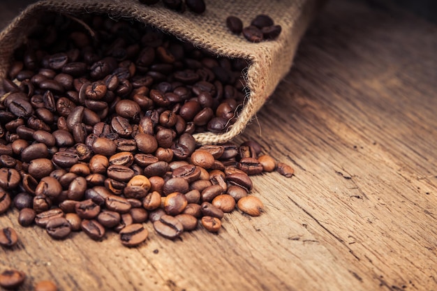 Vista ad alta angolazione dei chicchi di caffè che cadono dal burlap sul tavolo