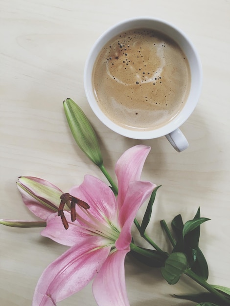 Vista ad alta angolazione del giglio rosa e della tazza di caffè sul tavolo