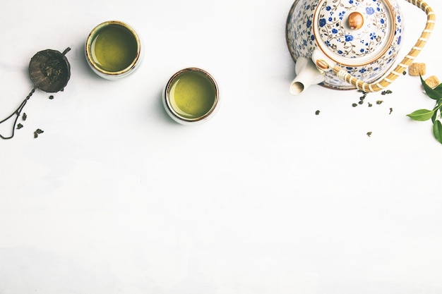 Vista ad alta angolazione del tè verde in tazza e bollitore su sfondo bianco