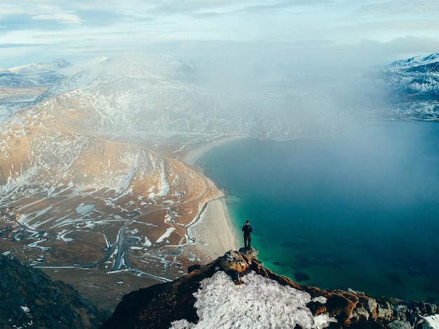 Vista ad alta angolazione dell'uomo in piedi sulla montagna vicino al mare