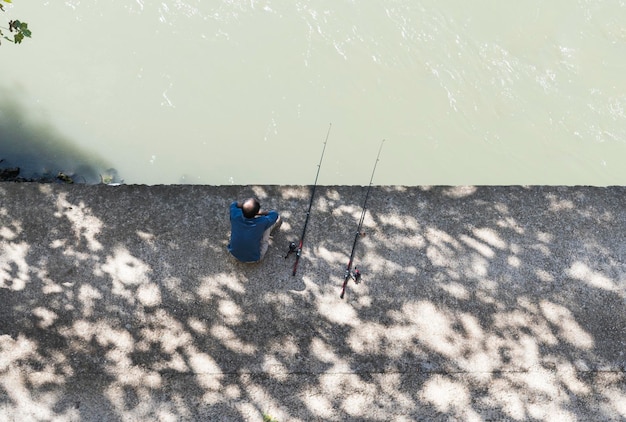 Vista ad alta angolazione dell'uomo sul molo sopra il fiume durante l'inverno