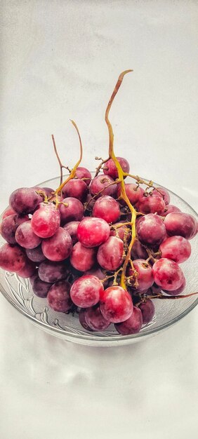 Vista ad alta angolazione dell'uva rossa in una ciotola isolata su uno sfondo bianco