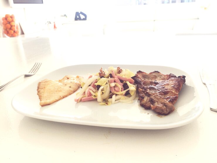Foto vista ad alta angolazione della carne con l'insalata servita in piatto sulla tavola