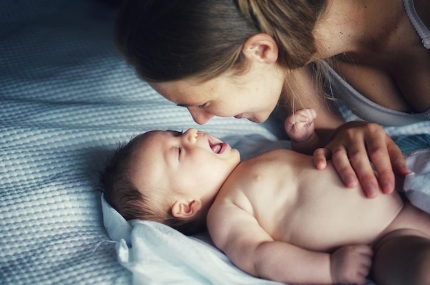 Vista ad alta angolazione della madre che gioca con il figlio carino sdraiato sul letto a casa