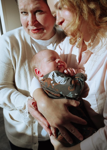 Vista ad alta angolazione della madre che porta il neonato e in piedi insieme a sua madre a casa