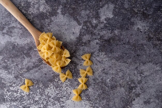 Vista ad alta angolazione di alcune farfalle pasta su sfondo di marmo grigio