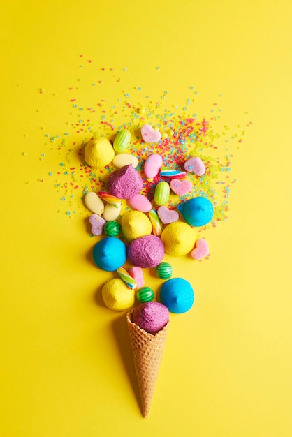 Vista ad alta angolazione di caramelle colorate su sfondo giallo