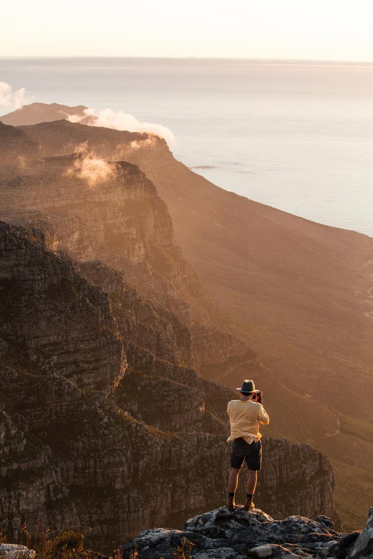 Foto vista ad alta angolazione di un uomo che fotografa il mare su montagne rocciose