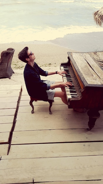 Vista ad alta angolazione di un uomo che suona il pianoforte sulla spiaggia