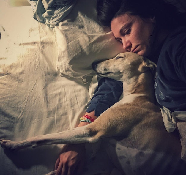 Vista ad alta angolazione di una donna che dorme con il cane sul letto