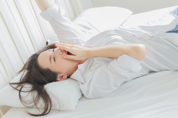 Vista ad alta angolazione di una donna che sbadiglia sul letto a casa