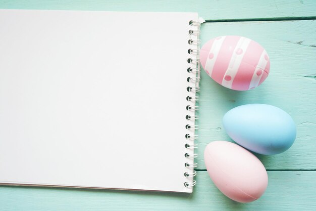 Vista ad alta angolazione di uova di Pasqua colorate con un libro bianco sul tavolo