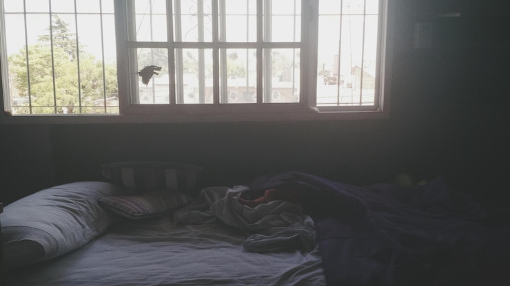 Foto vista ad alto angolo del letto disordinato contro la finestra a casa
