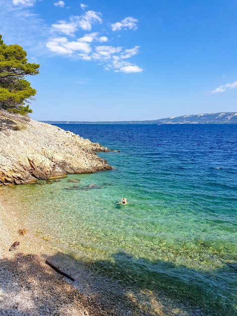 Vista ad alto angolo della donna sul lettino galleggiante della piscina che galleggia sul mare turchese.