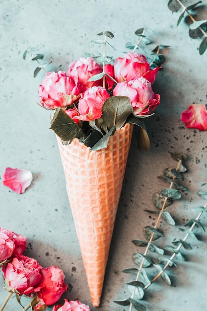 Vista ad alto angolo delle rose rosa nel cono di gelato sul tavolo