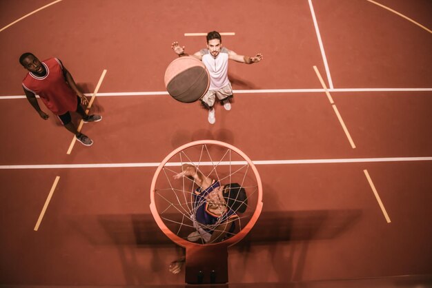 Vista ad alto angolo di bei ragazzi che giocano a basket all'aperto di notte