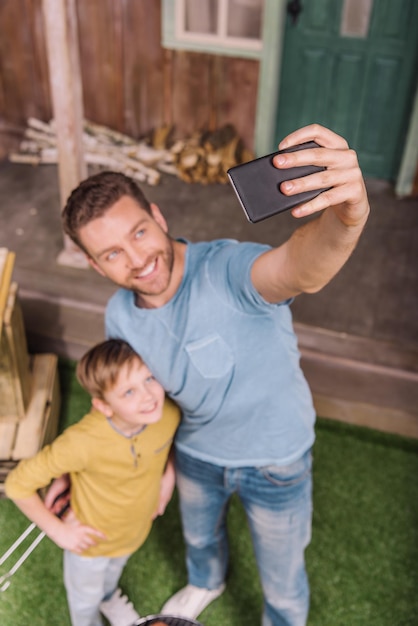 Vista ad alto angolo di padre e figlio sorridenti che prendono selfie
